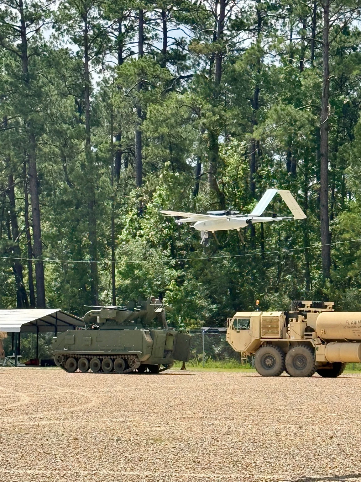ORKID 260 in flight above tracked and wheeled vehicles at a field site
